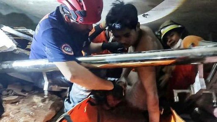 This handout photo taken and released on April 2, 2025 by the Myanmar Military Information Team shows a joint team of Myanmar and Turkish rescuers pulling a man alive from the rubble of a hotel in the capital Naypyidaw, five days after a major earthquake struck central Myanmar. The shallow 7.7-magnitude earthquake flattened buildings across Myanmar, killing more than 2,700 people and making thousands more homeless. (Photo by Handout / MYANMAR MILITARY INFORMATION TEAM / AFP) / RESTRICTED TO EDITORIAL USE - MANDATORY CREDIT 