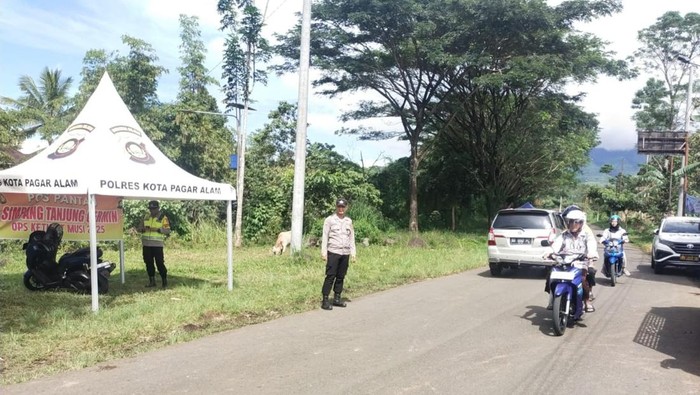 Petugas kepolisian saat mengatur lalu lintas kendaraan para wisatawan yang akan berkunjung ke wisata Gunung Dempo