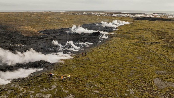 Potret Letusan Gunung Berapi di Islandia Scientists approach the southernmost part of the fissure to collect data following a volcanic eruption near the town of Grindavik, on the Reykjanes Peninsula, Iceland, Tuesday, April 1, 2025. (AP Photo/Marco di Marco)