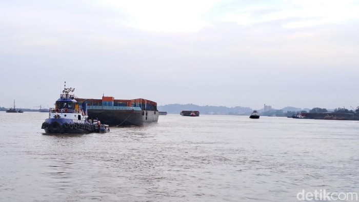 Sebuah tongkang kosong melaju yang ditarik oleh kapal di Sungai Mahakam menandakan ritme industri yang tak pernah berhenti di jalur sungai utama Kalimantan Timur Sebuah tongkang kosong melaju yang ditarik oleh kapal di Sungai Mahakam menandakan ritme industri yang tak pernah berhenti di jalur sungai utama Kalimantan Timur