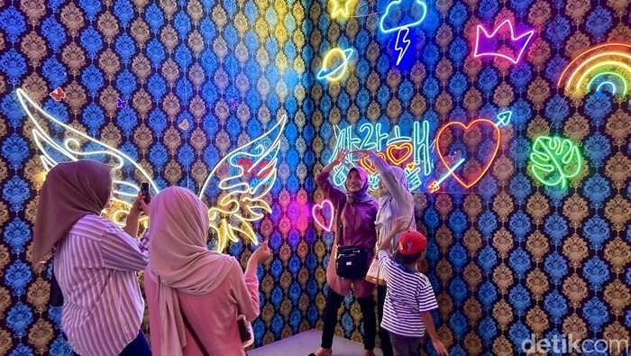 Pengunjung berpose saat foto di Lighting Art Kota Tua, Jakarta, Kamis (3/4/2025).