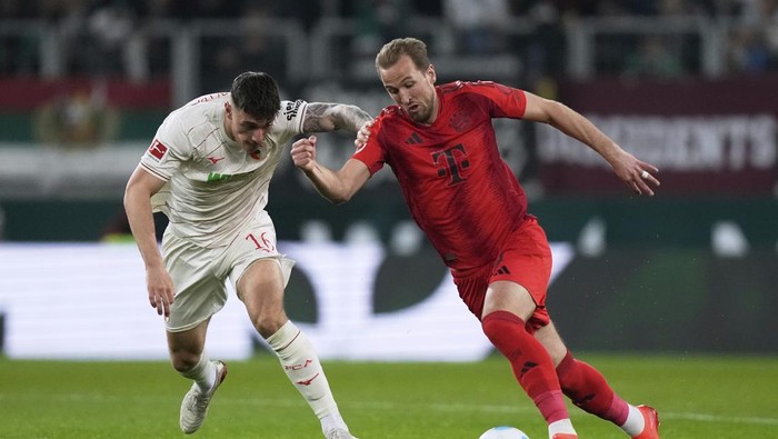 Augsburgs Cedric Zesiger, left, and Bayerns Harry Kane fight for the ball during the German Bundesliga soccer match between Augsburg and Bayern Munich in Augsburg, Friday, April 4, 2025. (AP Photo/Matthias Schrader)