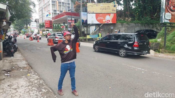 Juru Parkir di Objek Wisata Lembang Mengarahkan kendaraan