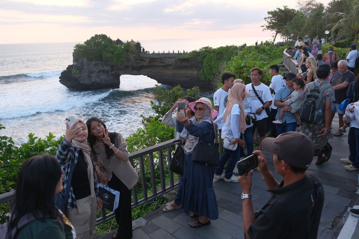 Wisatawan menikmati suasana saat libur Lebaran di Daya Tarik Wisata (DTW) Tanah Lot, Tabanan, Bali, Sabtu (5/4/2025). Pengelola objek wisata mencatat pada masa libur Lebaran 31 Maret-4 April 2025 jumlah kunjungan wisatawan ke objek wisata itu sebanyak 35.000 orang dengan persentase yakni 70 persen wisatawan dometik dan 30 persen wisatawan mancanegara. ANTARA FOTO/Nyoman Hendra Wibowo/tom.