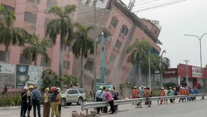 Rescue workers stand on the street next to a collapsed building in Mandalay on April 5, 2025, following the March 28 earthquake. The shallow 7.7-magnitude earthquake on March 28 flattened buildings across Myanmar, killing more than 3,000 people and making thousands more homeless. (Photo by Zaw Htun / AFP)