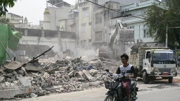 A man rides on a motorbike past a collapsed building in Kyaukse Township on April 4, 2025, one week after the March 28 earthquake. The shallow 7.7-magnitude earthquake on March 28 flattened buildings across Myanmar, killing more than 3,000 people and making thousands more homeless. (Photo by Sai Aung MAIN / AFP)