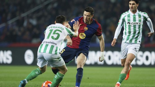 Barcelonas Robert Lewandowski, center, is challenged by Betis Romain Perraud, left, during a Spanish La Liga soccer match between Barcelona and Real Betis at the Lluis Companys Olympic stadium in Barcelona, Spain, Saturday, April 5, 2025. (AP Photo/Joan Monfort)