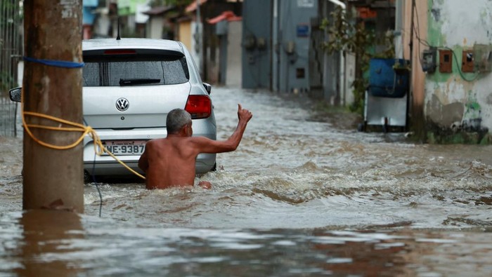 Penampakan Banjir Terjang Rio de Janeiro Brasil People gather next to a firefighters's dinghy on a street after heavy rains in Parque Mambucaba neighbourhood in Angra dos Reis, state of Rio de Janeiro, Brazil April 5, 2025. REUTERS/Aline Massuca