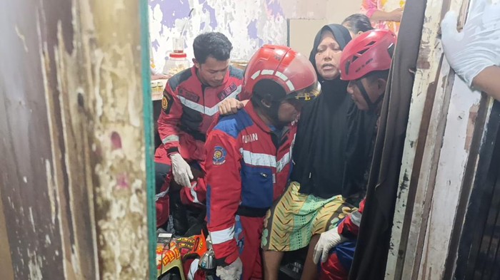 Petugas Damkarmat Makassar mengevakuasi wanita stroke dari lantai 2 rumahnya.
