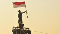 Peserta mengibarkan bendera merah putih saat mengikuti lomba panjat pinang di kawasan Pantai Demaan, Kelurahan Demaan, Jepara, Jawa Tengah.