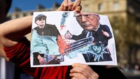 Seseorang memegang plakat saat orang-orang menghadiri Hands Off! demonstrasi menentang Presiden AS Donald Trump dan penasihatnya Elon Musk sebagai bagian dari gerakan anti-Trump dan anti-Tesla di seluruh dunia, di Place de la Republique di Paris, Prancis, 5 April 2025. REUTERS/Abdul Saboor.