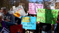 Demonstran memegang plakat saat anggota dan pendukung Democrats Abroad menyerukan sesama warga Amerika yang tinggal di Jerman untuk memprotes mengakhiri kekacauan di dalam negeri dan terhadap Presiden AS Donald Trump dan penasihatnya Elon Musk di Berlin, Jerman, 5 April 2025. REUTERS/Christian Mang.