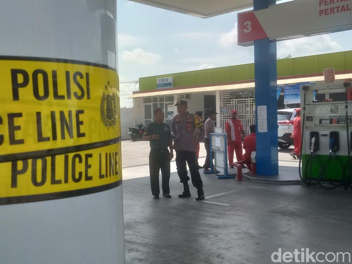 Anggota Sat Reskrim Polres Klaten memasang garis polisi di SPBU Trucuk, Klaten, Selasa (8/4/2025).