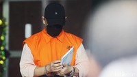 Afrian Jafar yang memakai topi hitam dan masker terus menunduk saat meninggalkan gedung KPK.
