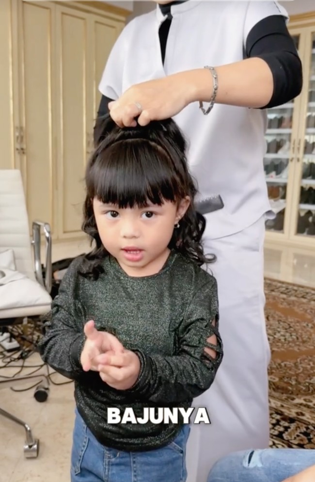 Rambut Ameena juga diikat setengah. Selama proses styling rambutnya, Ameena yang mengenakan baju lengan panjang dipadukan celana jeans itu terlihat anteng menunggu rambutnya selesai ditata. Foto: TikTok/@aureliehermansyahatta