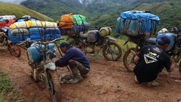 Pengemudi ojek memperbaiki sepeda motornya yang mengangkut jeriken berisi bahan bakar minyak (BBM) di Desa Embonatana, Kecamatan Seko, Kabupaten Luwu Utara, Sulawesi Selatan, Rabu (9/4/2025). Distribusi BBM ke daerah terpencil tersebut menggunakan jasa ojek dengan tarif Rp100 ribu per jeriken untuk memenuhi kebutuhan warga setempat dengan harga eceran untuk jenis pertalite Rp20 ribu per liter dan solar Rp15 ribu per liter. ANTARA FOTO/Arnas Padda/tom.