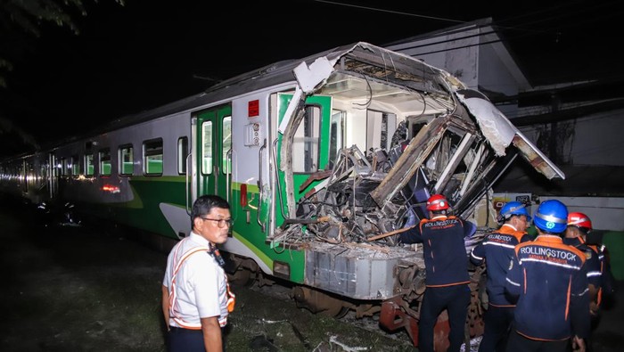 Sejumlah petugas mengevakuasi truk bermuatan kayu yang tertabrak kereta api commuter line Jenggala di Desa Tenggulunan, Kebomas, Gresik, Jawa Timur, Selasa (8/4/2025). Kereta api commuter line Jenggala relasi Gresik-Sidoarjo tersebut bertabrakan dengan truk bermuatan kayu di jalur perlintasan langsung (JPL) KM 7+600 antara Stasiun Indro-Kandangan Gresik dan mengakibatkan satu orang asisten masinis meninggal dunia dan satu orang masinis mengalami luka berat. ANTARA FOTO/Rizal Hanafi/Spt.