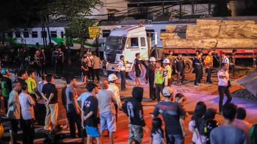 Sejumlah petugas mengevakuasi truk bermuatan kayu yang tertabrak kereta api commuter line Jenggala di Desa Tenggulunan, Kebomas, Gresik, Jawa Timur, Selasa (8/4/2025). Kereta api commuter line Jenggala relasi Gresik-Sidoarjo tersebut bertabrakan dengan truk bermuatan kayu di jalur perlintasan langsung (JPL) KM 7+600 antara Stasiun Indro-Kandangan Gresik dan mengakibatkan satu orang asisten masinis meninggal dunia dan satu orang masinis mengalami luka berat. ANTARA FOTO/Rizal Hanafi/Spt.