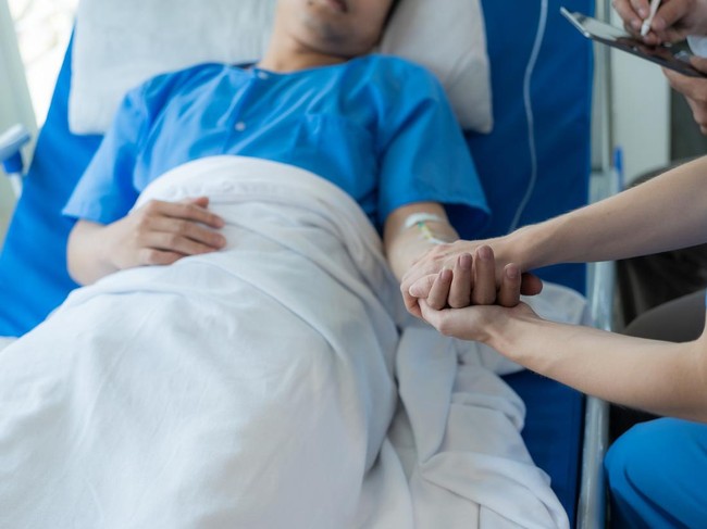 Man holding hand, giving support and comfort to woman, loved one sick in hospital bed.