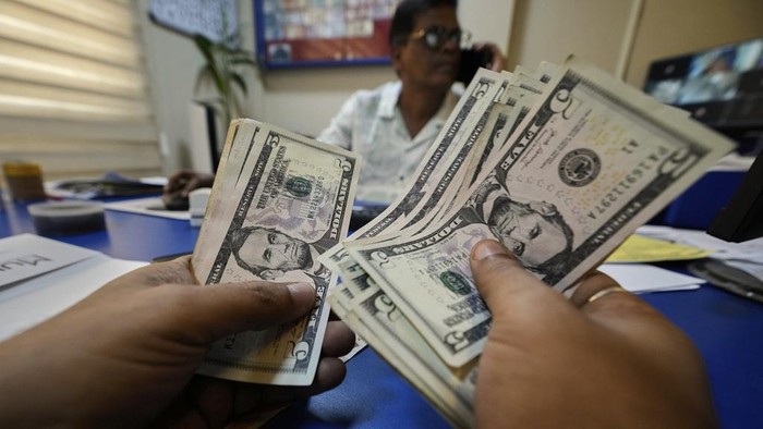 Perang Dagang Trump Berlaku Mulai Hari Ini, Bikin Kacau Dunia! A customer counts dollars inside a forex shop in Guwahati, India, Tuesday, April 8, 2025. (AP Photo/Anupam Nath)