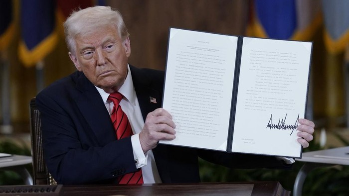 President Donald Trump holds up a signed executive order in the East Room of the White House in Washington, Thursday, March 20, 2025. (AP Photo/Jose Luis Magana)