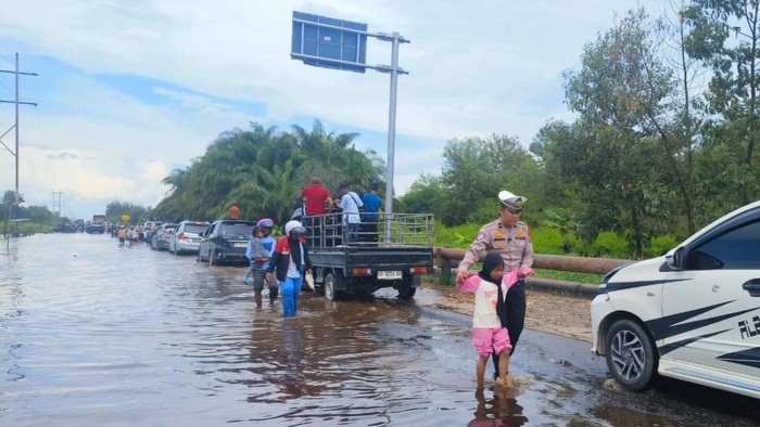 Personel Satlantas saat membantu warga melintasi lokasi terendam banjir (Dok Polsek Bungaraya)