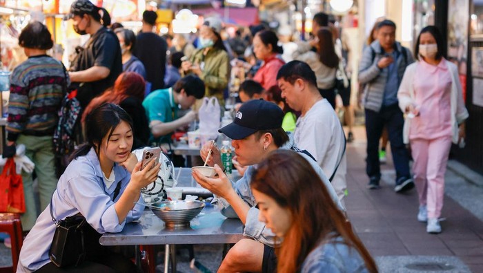 People sit near food stalls at a nightmarket in Taipei, Taiwan April 8, 2025. REUTERS/Ann Wang