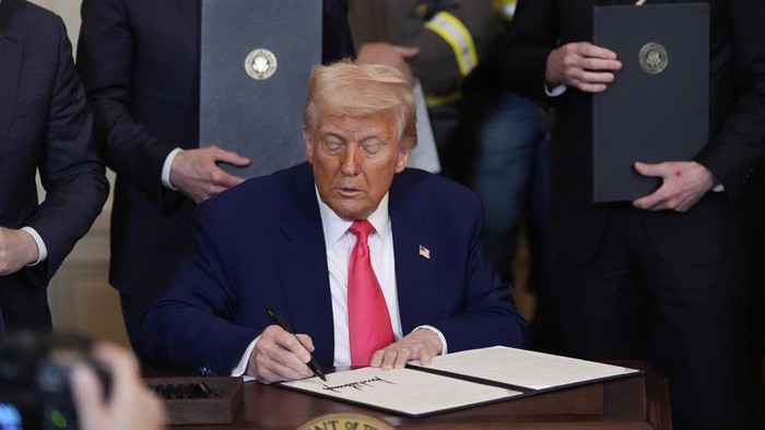 President Donald Trump signs an executive order during an event in the East Room of the White House, Tuesday, April 8, 2025, in Washington. (AP Photo/Alex Brandon)
