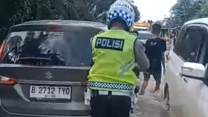 Polisi dibantu warga dorong kendaraan di lokasi banjir agar tak mogok.