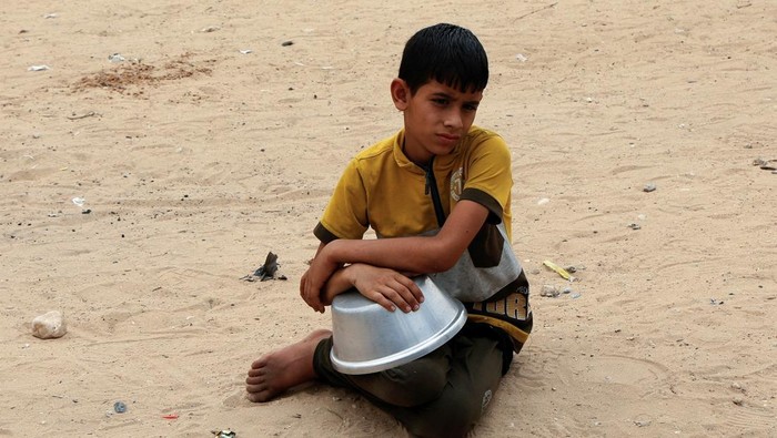 Tatapan Anak Gaza Saat Antre Makan Palestinians gather to receive food cooked by a charity kitchen, in Khan Younis, southern Gaza Strip, April 8, 2025. REUTERS/Hatem Khaled