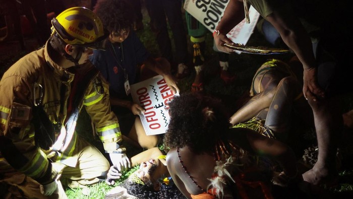 A firefighter assists an Indigenous woman who is affected by tear gas fired by riot police while taking part in the Terra Livre (Free Land) protest camp to demand the demarcation of land and to defend cultural rights, in Brasilia, Brazil April 10, 2025. REUTERS/Adriano Machado