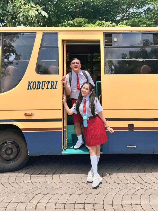 Dari foto-foto yang dibagikan ke Instagram terlihat Denny dan Bella yang berpose di depan sebuah bus dengan mengenakan pakaian seragam putih-merah. Tamasya, tulis keterangan dalam unggahannya. Foto: Instagram/@denny_caknan