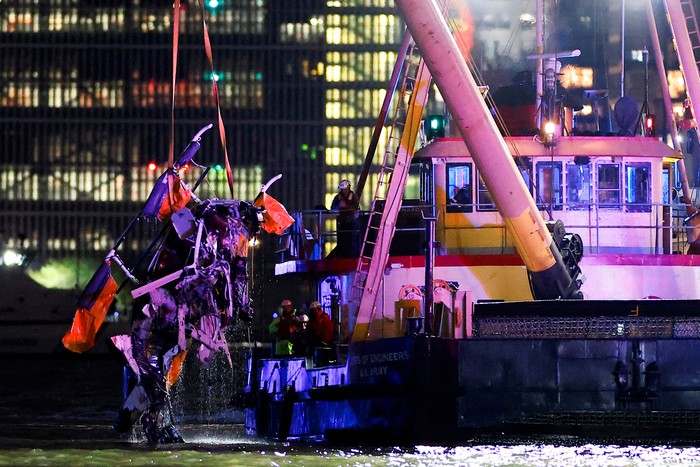 People look on from a building as emergency personnel work at the scene of a helicopter crash on the Hudson River near lower Manhattan in New York, as seen from Newport, New Jersey U.S., April 10, 2025.  REUTERS/Eduardo Munoz