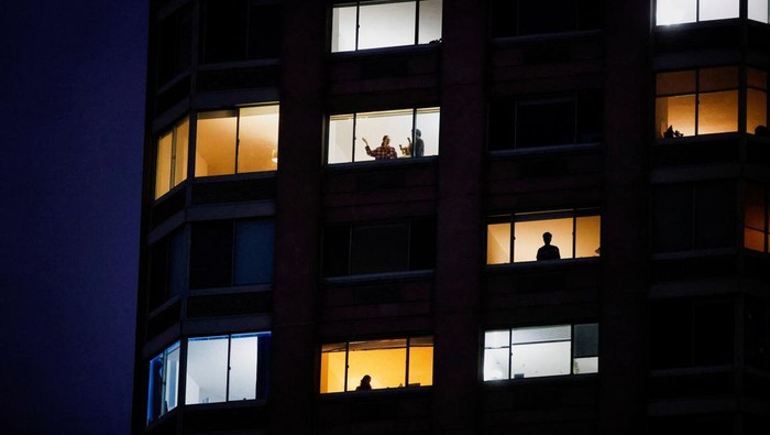 People look on from a building as emergency personnel work at the scene of a helicopter crash on the Hudson River near lower Manhattan in New York, as seen from Newport, New Jersey U.S., April 10, 2025.  REUTERS/Eduardo Munoz
