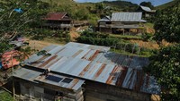 Foto udara seorang warga melakukan perawatan panel surya di atas atap rumahnya di Desa Embonatana, Kecamatan Seko, Sulawesi Selatan, Kamis (10/4/2025).  