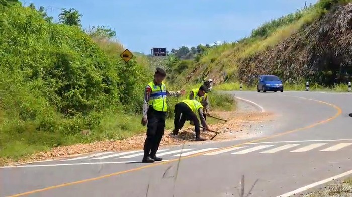 Personel Polres Blitar membersihkan jalan dari kerikil di JLS