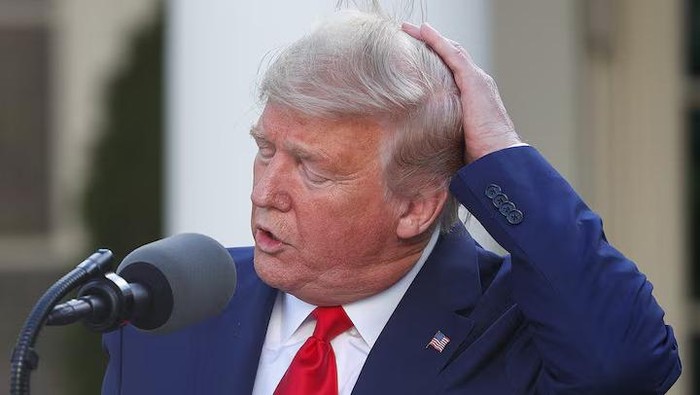 U.S. President Donald Trump holds onto his hair in a gust of wind as he addresses a briefing in the Rose Garden at the White House in Washington, March 30, 2020. REUTERS/Tom Brenner/File Photo Purchase Licensing Rights