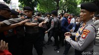 Polisi berupaya mengamankan bentrokan dua kubu tersebut. 