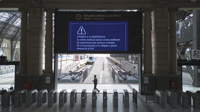 A lone worker walks inside the Retiro train station that is empty due to a general strike against the austerity measures of President Javier Milei in Buenos Aires, Argentina, Thursday, April 10, 2025. (AP Photo/Rodrigo Abd)
