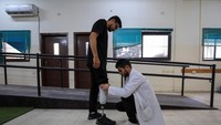 Seorang dokter memasangkan kaki palsu kepada seorang warga Gaza.  