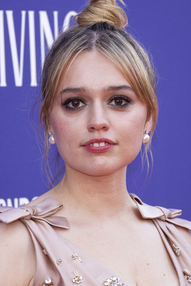 Aimee Lou Wood. Aktris asal Inggris ini dikenal dengan gigi depan yang sedikit menonjol dan celah tipis di antaranya. Senyumnya terlihat tulus dan hangat, memberikan kesan innocent sekaligus quirky yang khas. Foto: Vianney Le Caer/Invision/AP/Vianney Le Caer