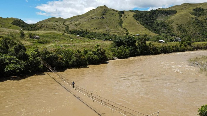 Foto udara warga melintas di atas jembatan gantung di Dusun Sae, Desa Embonatana, Kecamatan Seko, Kabupaten Luwu Utara, Sulawesi Selatan, Sabtu (12/4/2025). Jembatan gantung dengan panjang sekitar 90 meter yang membentang di atas Sungai Karama tersebut menjadi akses alternatif warga setempat untuk mempersingkat jarak tempuh ke lahan pertanian mereka. ANTARA FOTO/Arnas Padda/YU