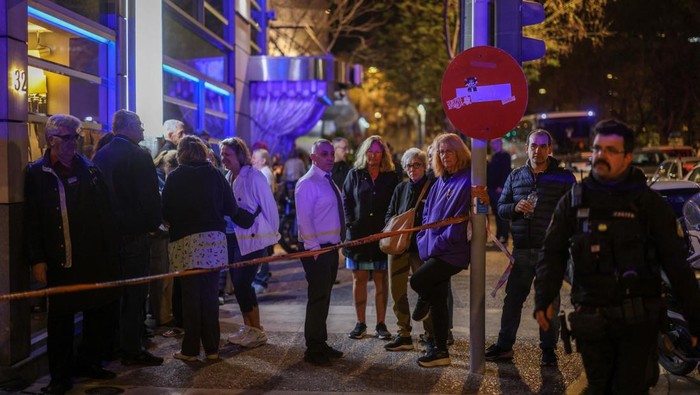 Bom Rakitan Meledak di Kantor Kereta Api Yunani Customers and staff of a nearby hotel stand behind. police cordon, following a bomb blast outside the Hellenic Train offices, in Athens, Greece, April 11, 2025. REUTERS/Stelios Misinas