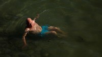 Seorang wisatawan tampak berendam di pantai.