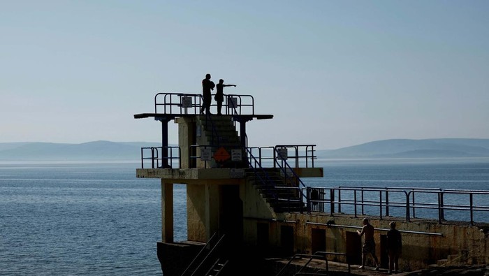 People stand on top of the Blackrock Diving Tower as they enjoy hot weather on the beach, in Galway, Ireland April 10, 2025. REUTERS/Clodagh Kilcoyne