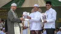 Ketua Utama Alkhairaat Habib Alwi bin Saggaf Aljufri (kiri) menyerahkan buku biografi Habib Idrus bin Salim Aljufri atau Guru Tua, pendiri perguruan Alkhairaat kepada Menteri Hukum Supratman Andi Agtas (kiri) dan Menteri ATR/Kepala BPN Nusron Wahid (tengah) pada haul ke-57 di Palu, Sulawesi Tengah, Sabtu (12/4/2025).