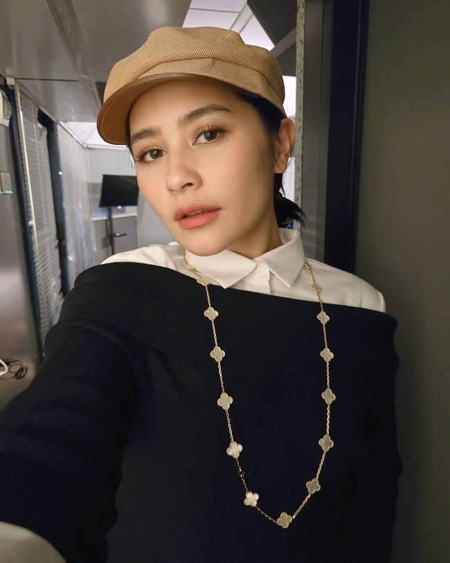 Ia bergaya dengan blus putih yang dibungkus luaran off-shoulder hitam yang dipadu kalung panjang menjuntai. (Foto: Instagram/@prillylatuconsina96)