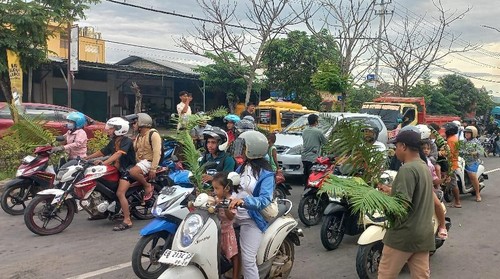 Remaja masjid  membagikan daun palem kepada umat Katolik di Labuan Bajo, Manggarai Barat, NTT, Sabtu (12/4/2025).