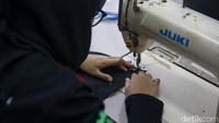 Seorang peserta pelatihan belajar menjahit.  