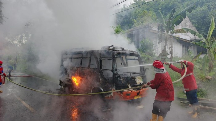 Petugas damkar berusaha memadamkan api yang membakar bus mikro berpenumpang di jalan raya Desa Kedungrandu, Kecamatan Patikraja, Kabupaten Banyumas, Senin (14/4/2025).